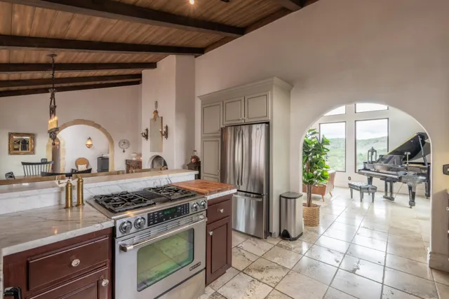 a kitchen with stainless steel appliances granite countertop a stove a refrigerator a dining table and chairs with the living room view