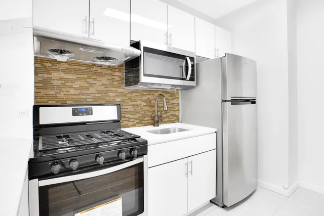 a kitchen that has a microwave a stove and white cabinets