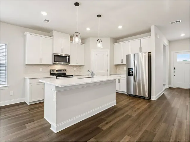 a kitchen with stainless steel appliances a refrigerator a stove a sink and a center island