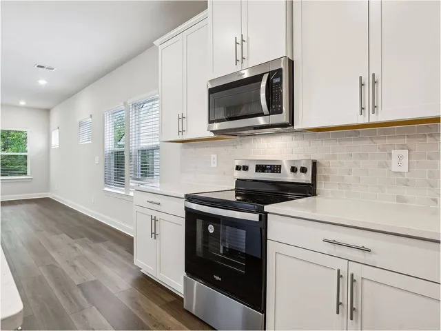 a kitchen with stainless steel appliances granite countertop a sink a stove a microwave and wooden floors