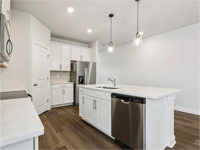 a kitchen with a sink a stove a refrigerator and white cabinets