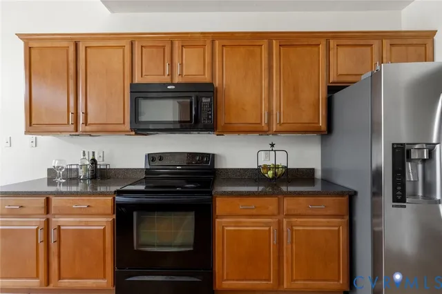 a kitchen with granite countertop a stove top oven microwave and cabinets