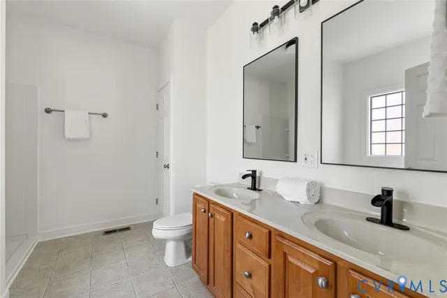 a bathroom with a double vanity sink toilet and mirror