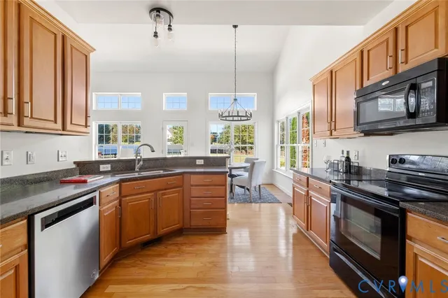 a kitchen with stainless steel appliances granite countertop a stove a sink dishwasher and a microwave oven with wooden cabinets