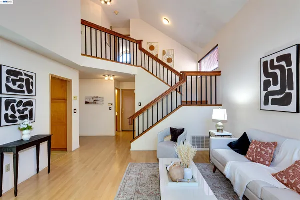 a living room with furniture and stairs with wooden floor