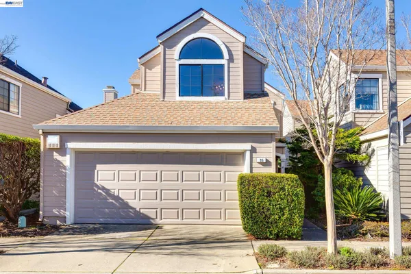 a view of a house with a small yard plants and large tree