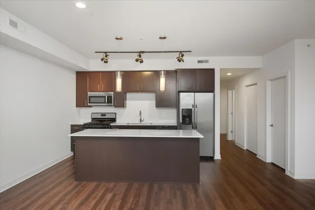 a kitchen with stainless steel appliances a sink stove and wooden floor