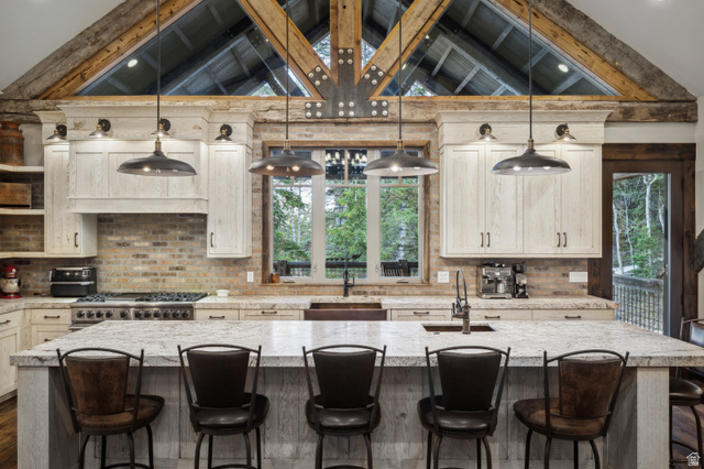 1667 West Tollgate Cyn Road Coalville, UT 84017 - Photo 9 of 61 Spacious kitchen featuring a large island with seating, a professional-grade range, light-toned cabinetry, exposed brick backsplash, and architectural ceiling beams