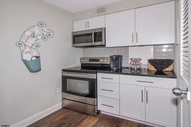 a kitchen with white cabinets stainless steel appliances and wooden floor