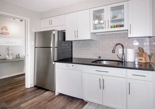 a kitchen with granite countertop white cabinets and refrigerator