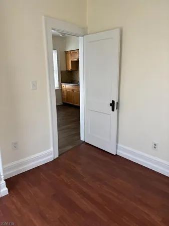 a view of an empty room with wooden floor and entrance