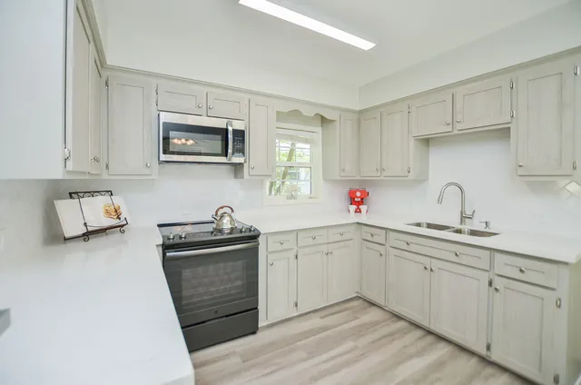 a kitchen with white cabinets sink and stainless steel appliances
