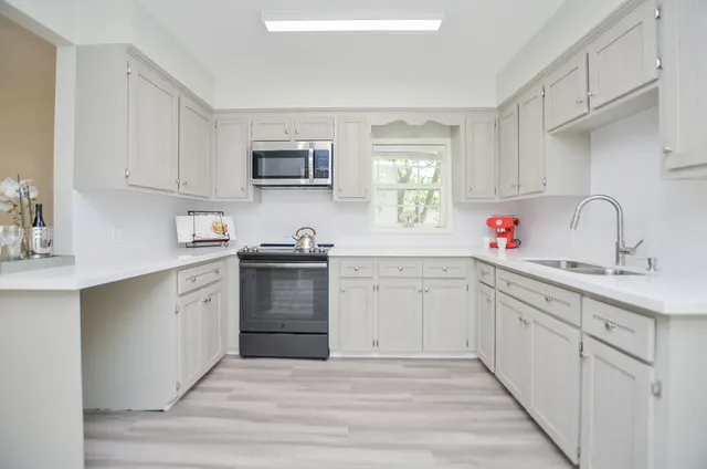 a kitchen with cabinets appliances a sink and a window