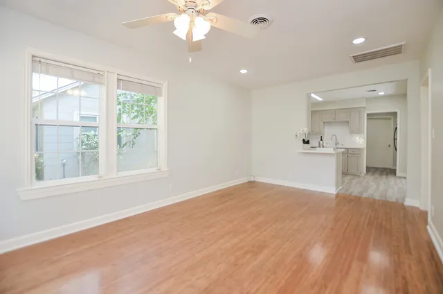 an empty room with wooden floor and windows