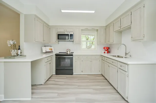a kitchen with white cabinets and sink
