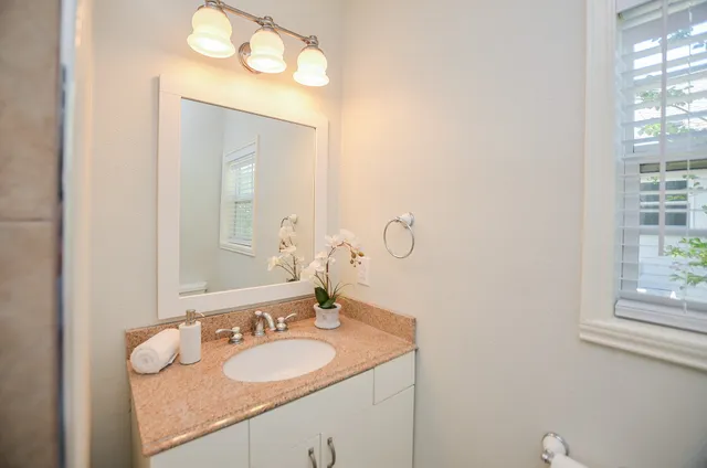 a bathroom with a granite countertop sink and a mirror