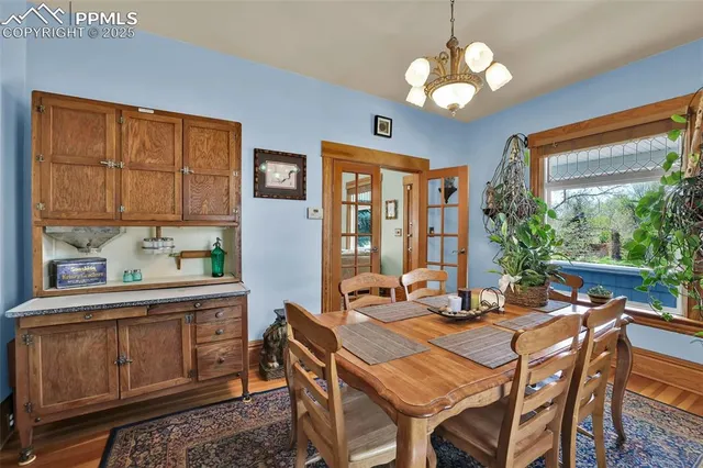 a dining room with wooden floor a chandelier a wooden table and chairs