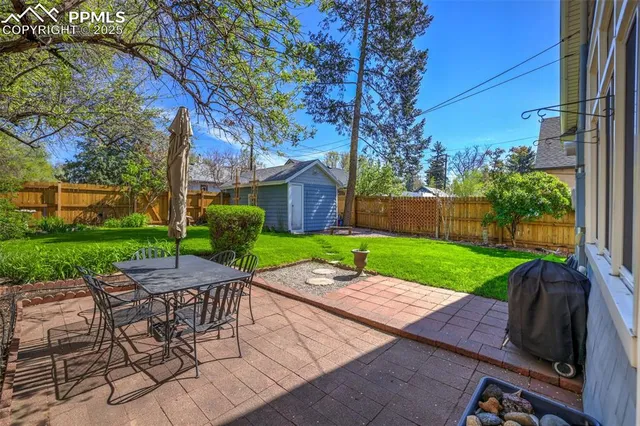 a view of a backyard with table and chairs and a large tree