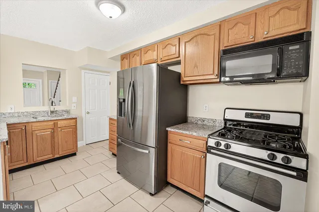 a kitchen with stainless steel appliances granite countertop a refrigerator stove and sink