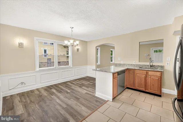 a large kitchen with granite countertop a sink cabinets and stainless steel appliances