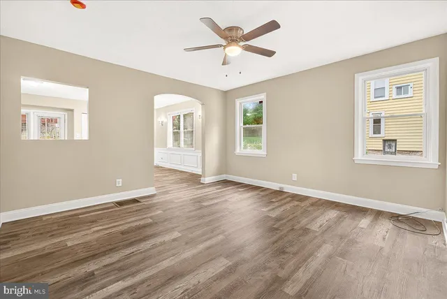 a view of an empty room with a window and wooden floor