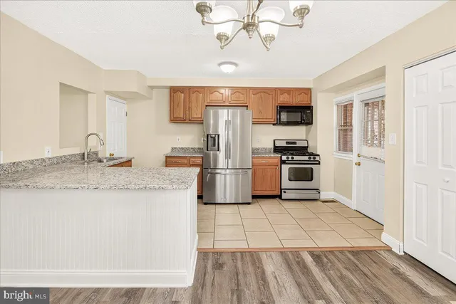 a kitchen with granite countertop a stove a sink and a refrigerator