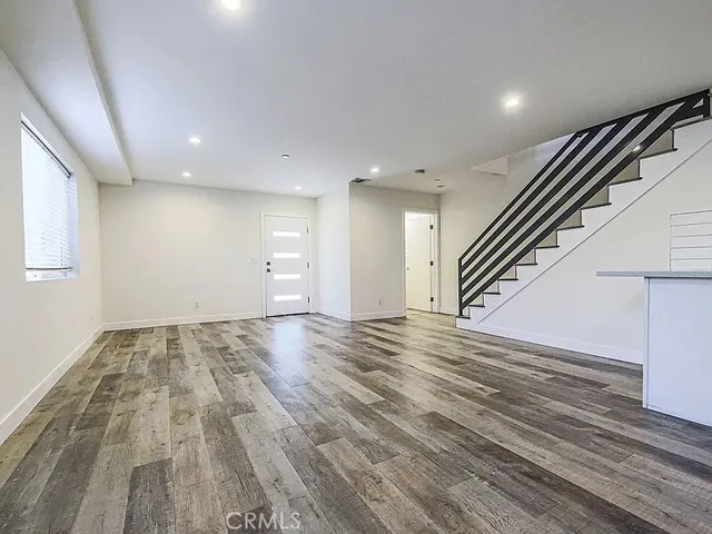 an empty room with wooden floor and stairs