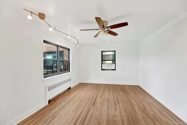 a view of empty room with wooden floor and fan