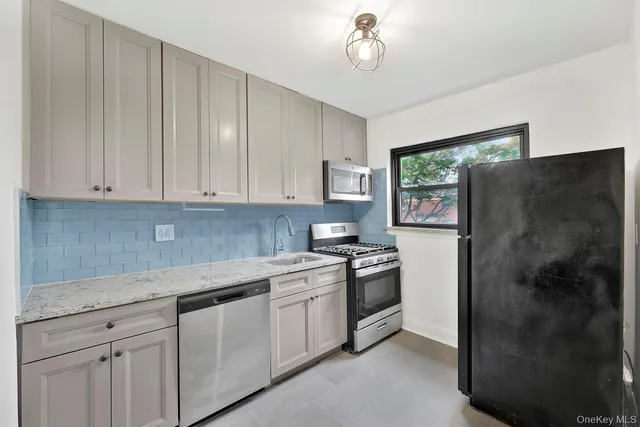 a kitchen with stainless steel appliances granite countertop a refrigerator a sink a stove and white cabinets