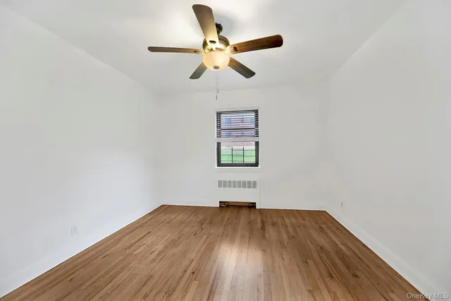 an empty room with wooden floor ceiling fan and windows