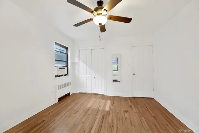 an empty room with wooden floor chandelier fan and windows