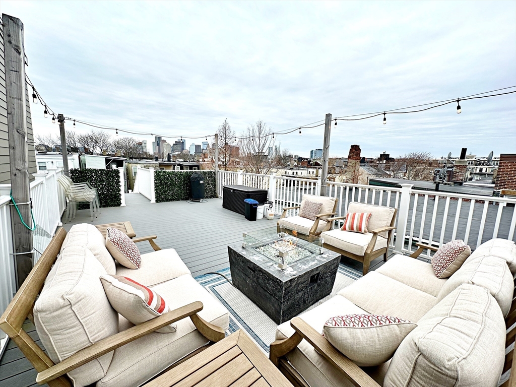 a roof deck with couches and potted plants with sky view