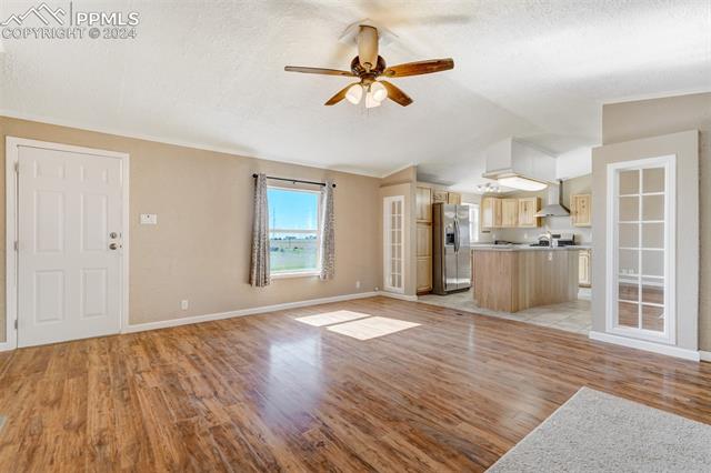 6240 Night Train Lane Yoder, CO 80864 - Photo 11 of 50 Unfurnished living room with a textured ceiling, ceiling fan, and light tile floors