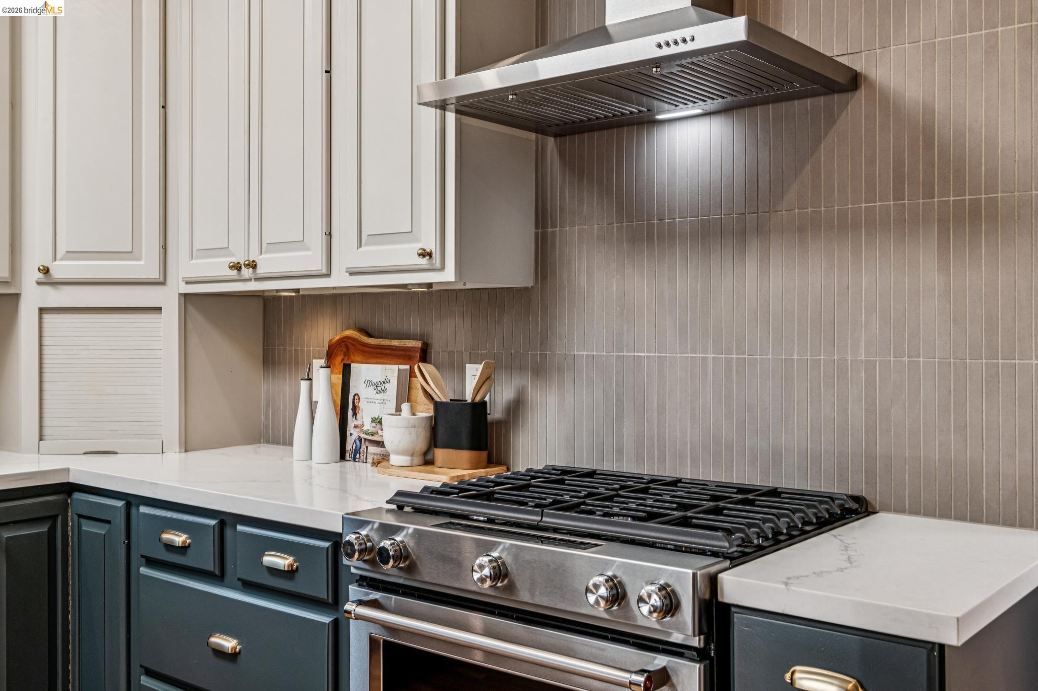 6521 Dover Street Berkeley, CA 94703 - Photo 24 of 80 Stainless steel gas range with coordinating ventilation hood, set against a tiled backsplash