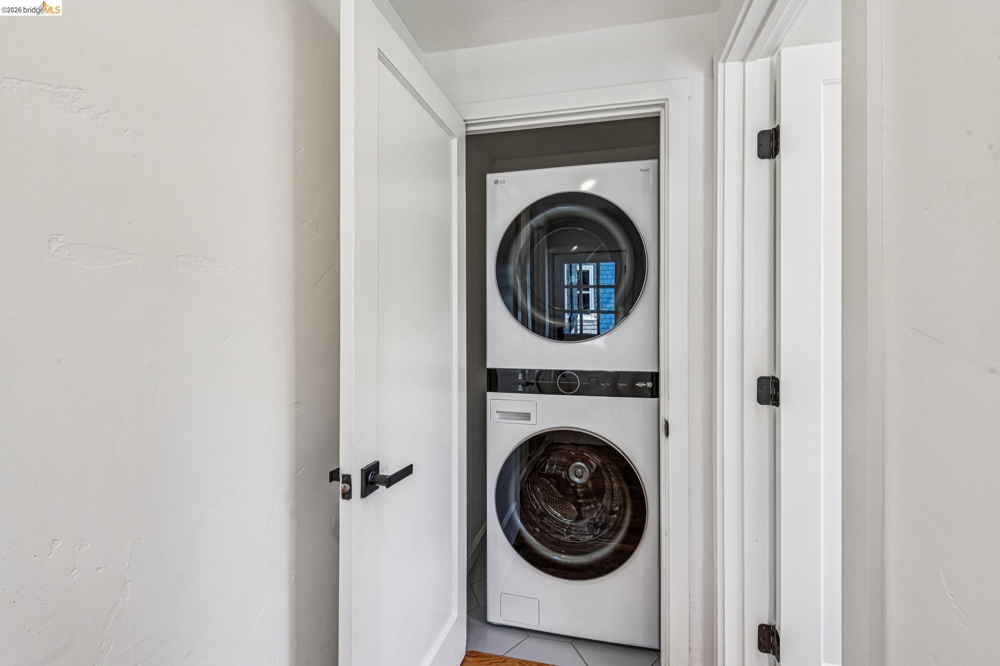 6521 Dover Street Berkeley, CA 94703 - Photo 30 of 80 Dedicated laundry closet featuring a stacked white washer and dryer unit, white paneled doors, and matte black hardware