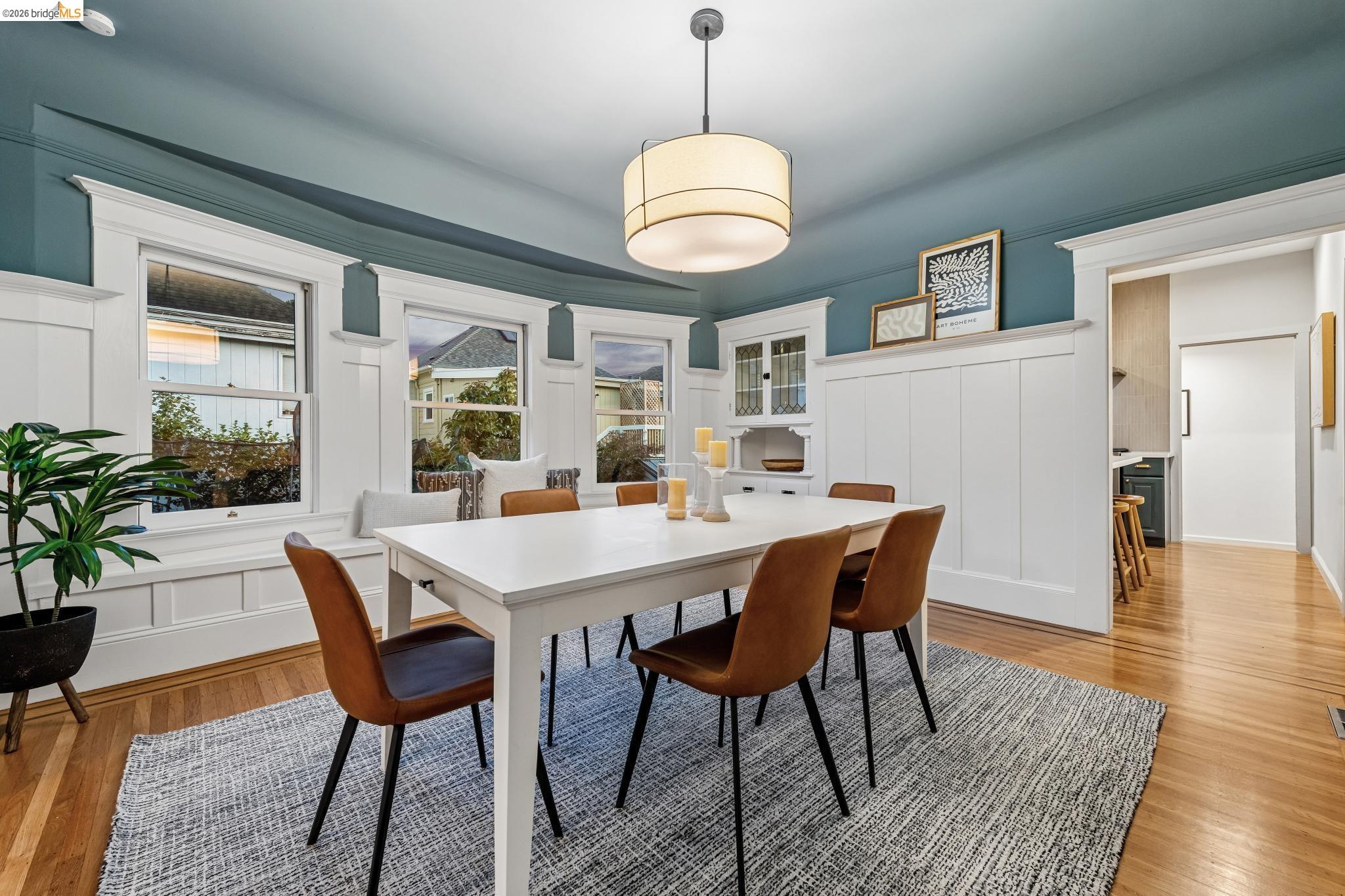 6521 Dover Street Berkeley, CA 94703 - Photo 65 of 80 Dining space featuring wood-finish flooring, a built-in window bench, white wainscoting, an integrated cabinet with glass doors, and a ceiling-mounted drum light fixture