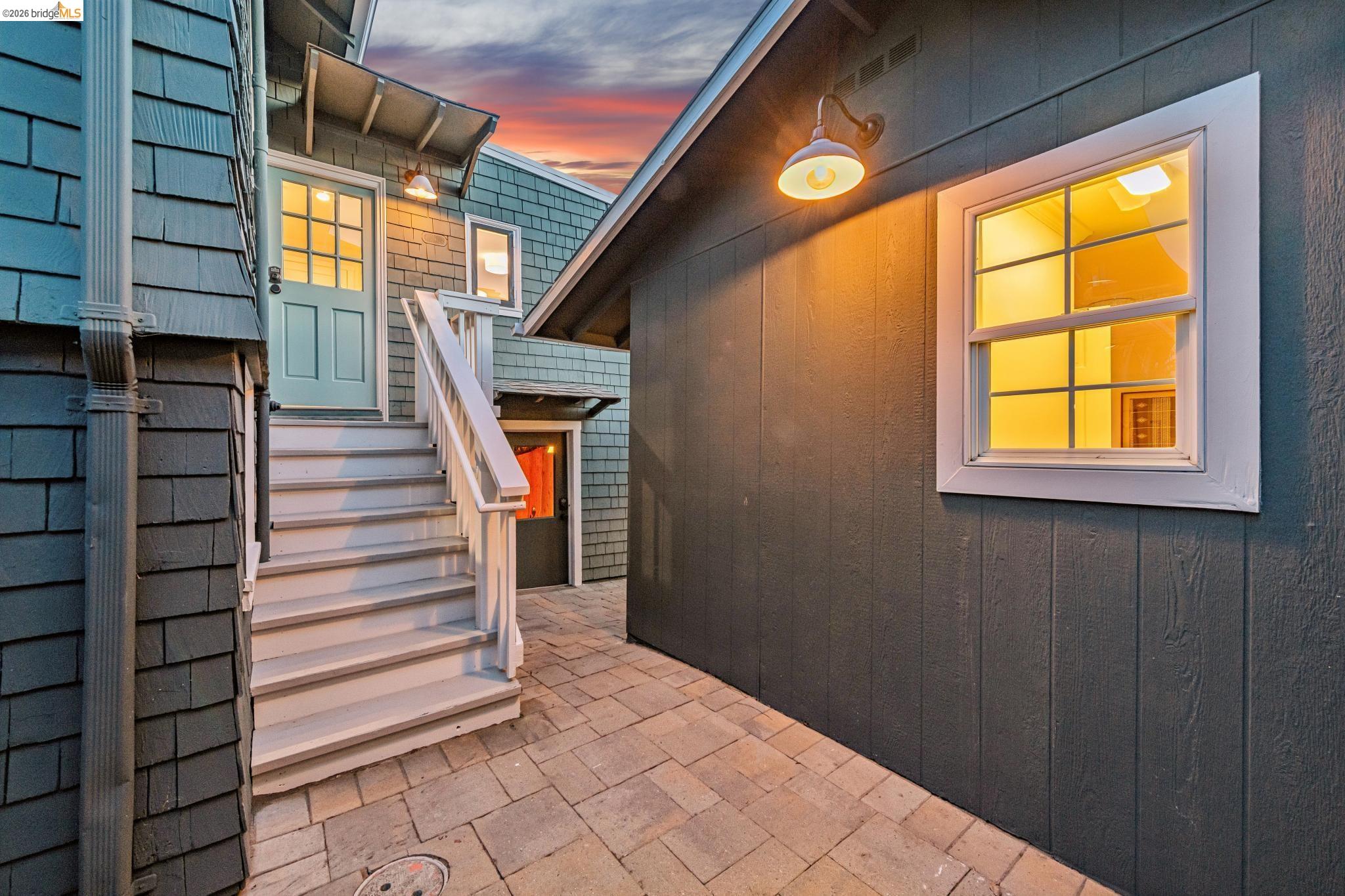 6521 Dover Street Berkeley, CA 94703 - Photo 68 of 80 Exterior featuring shingle and board-and-batten siding, a paved patio, and a light blue paneled entry door with glass inserts