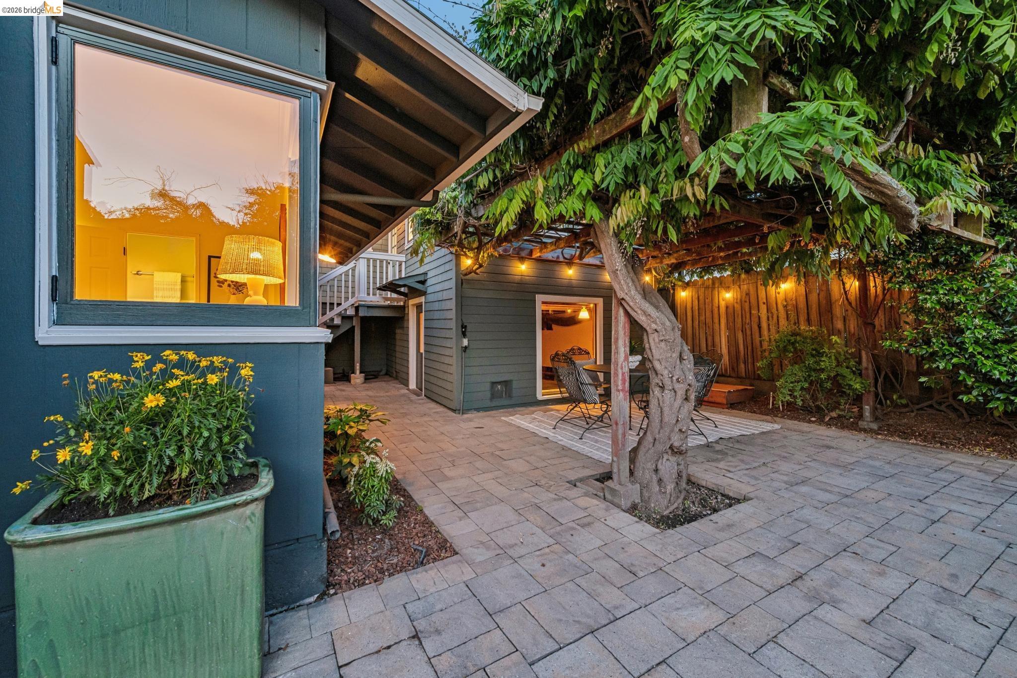 6521 Dover Street Berkeley, CA 94703 - Photo 71 of 80 Expansive paver patio featuring a mature tree with a wood pergola, string lighting, and a fenced perimeter