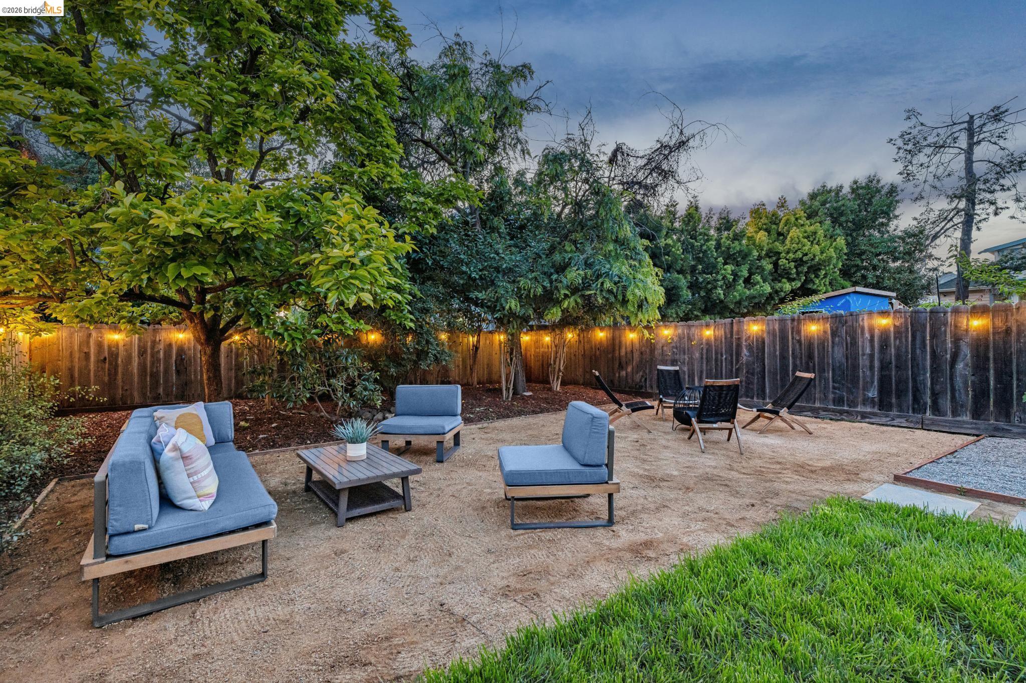 6521 Dover Street Berkeley, CA 94703 - Photo 77 of 80 Spacious backyard featuring a gravel patio area with a dedicated fire pit zone, complemented by a perimeter privacy fence and established trees