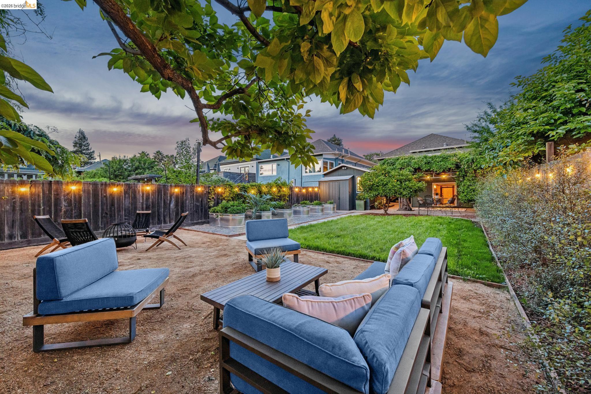 6521 Dover Street Berkeley, CA 94703 - Photo 79 of 80 Expansive backyard featuring a central manicured lawn, gravel patio areas, and a wooden privacy fence with string lighting