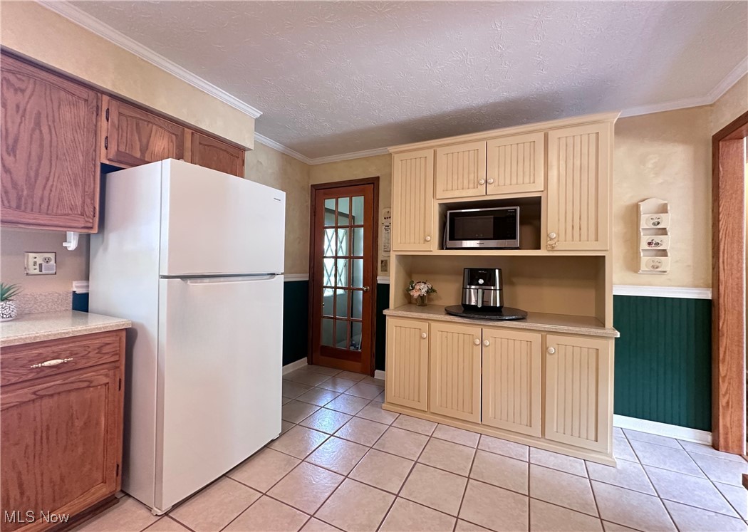 157 Birch Road Painesville, OH 44077 - Photo 8 of 41 Kitchen with freestanding refrigerator, stainless steel microwave, cream cabinetry, light countertops, and light tile patterned floors