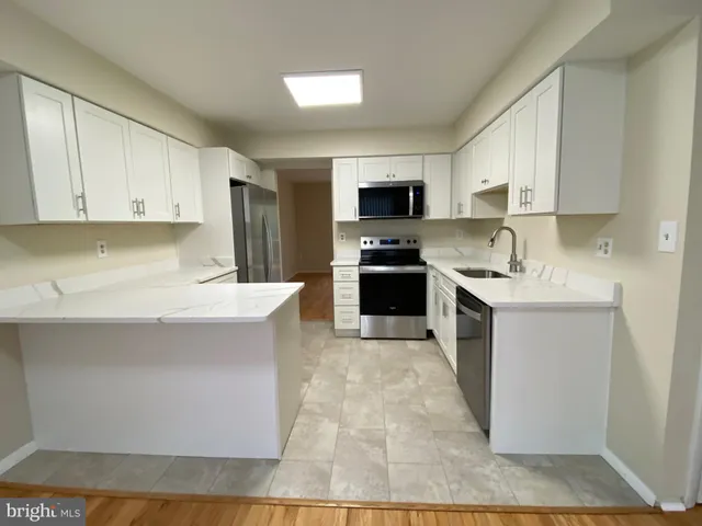 a kitchen with a sink a counter top space cabinets and stainless steel appliances
