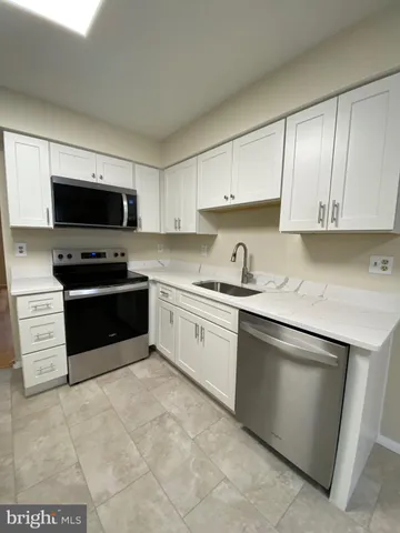 a kitchen with granite countertop a sink a stove and cabinets