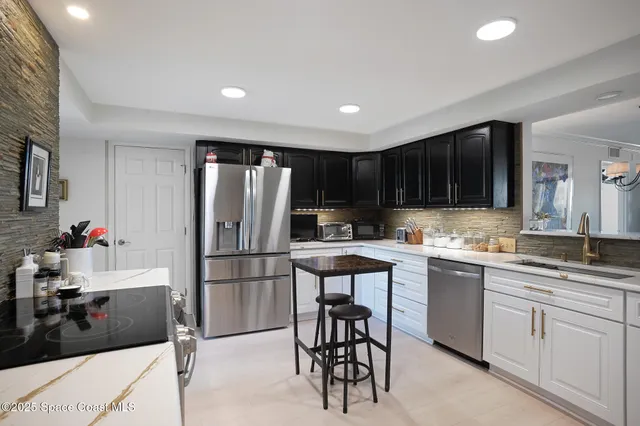 a kitchen with stainless steel appliances kitchen island granite countertop a refrigerator and a sink