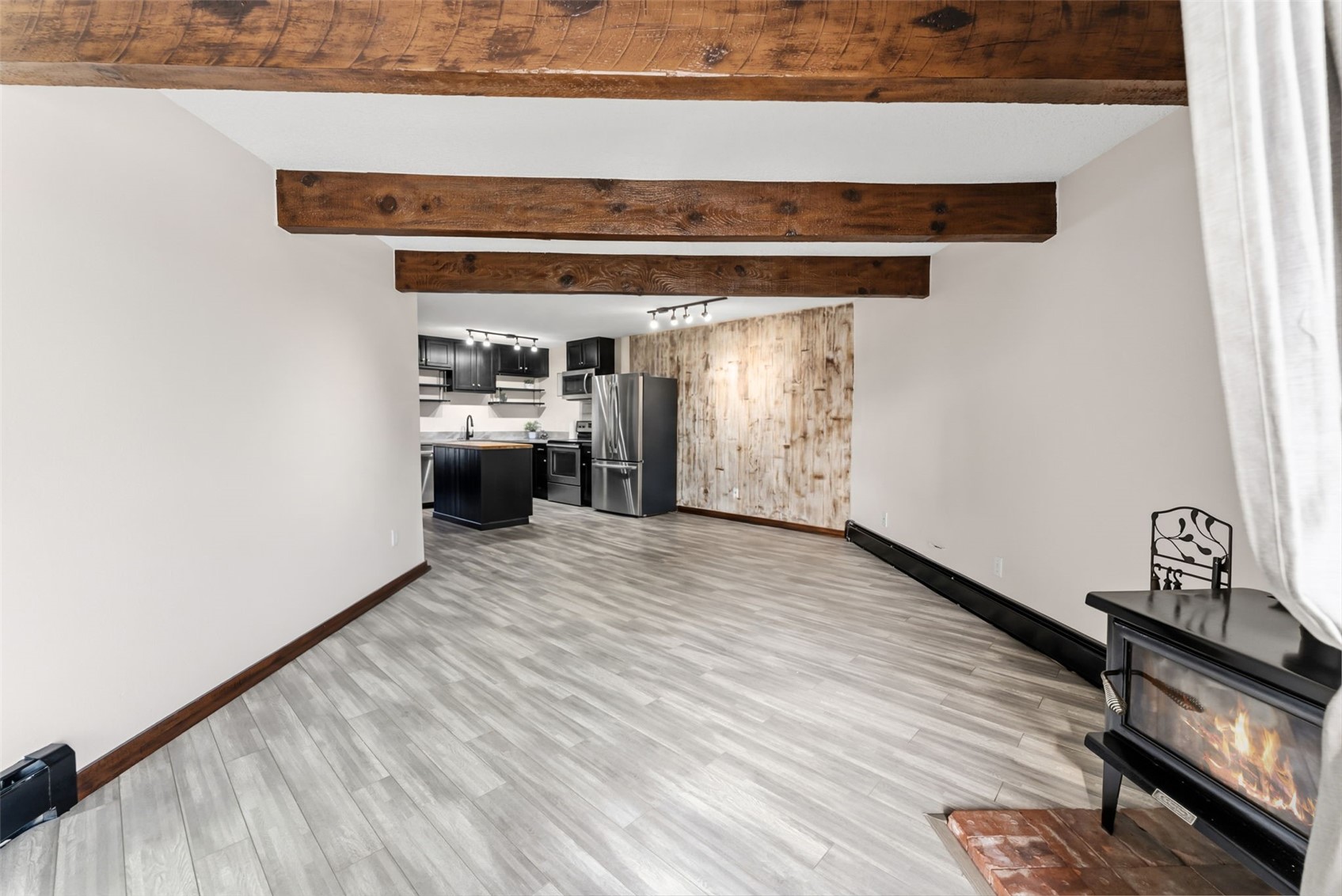 7124 Ryan Gulch Road, Unit 204 Wildernest, CO 80498 - Photo 15 of 36 Unfurnished living room with light wood finished floors, a wood stove, and beam ceiling