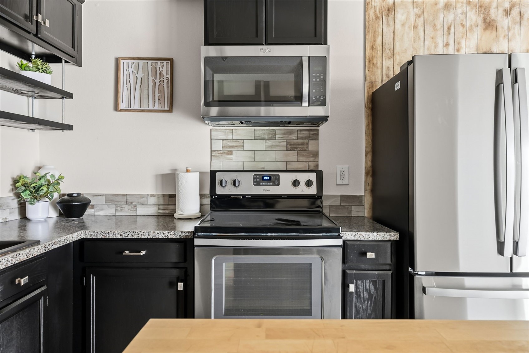 7124 Ryan Gulch Road, Unit 204 Wildernest, CO 80498 - Photo 21 of 36 Kitchen featuring stainless steel appliances, decorative backsplash, dark cabinets, open shelves, and light stone countertops