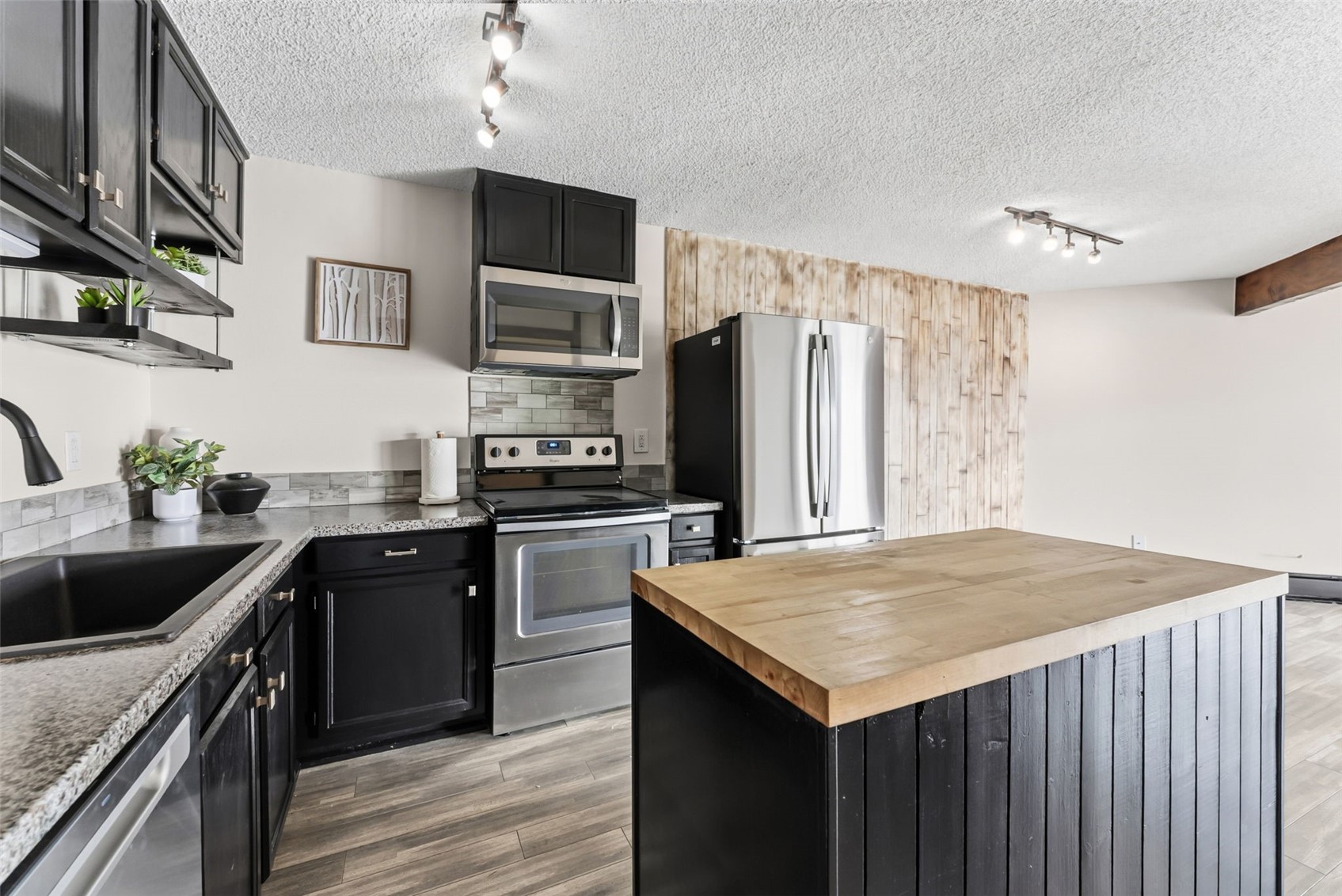 7124 Ryan Gulch Road, Unit 204 Wildernest, CO 80498 - Photo 23 of 36 Kitchen featuring dark cabinets, rail lighting, stainless steel appliances, a kitchen island, and butcher block counters