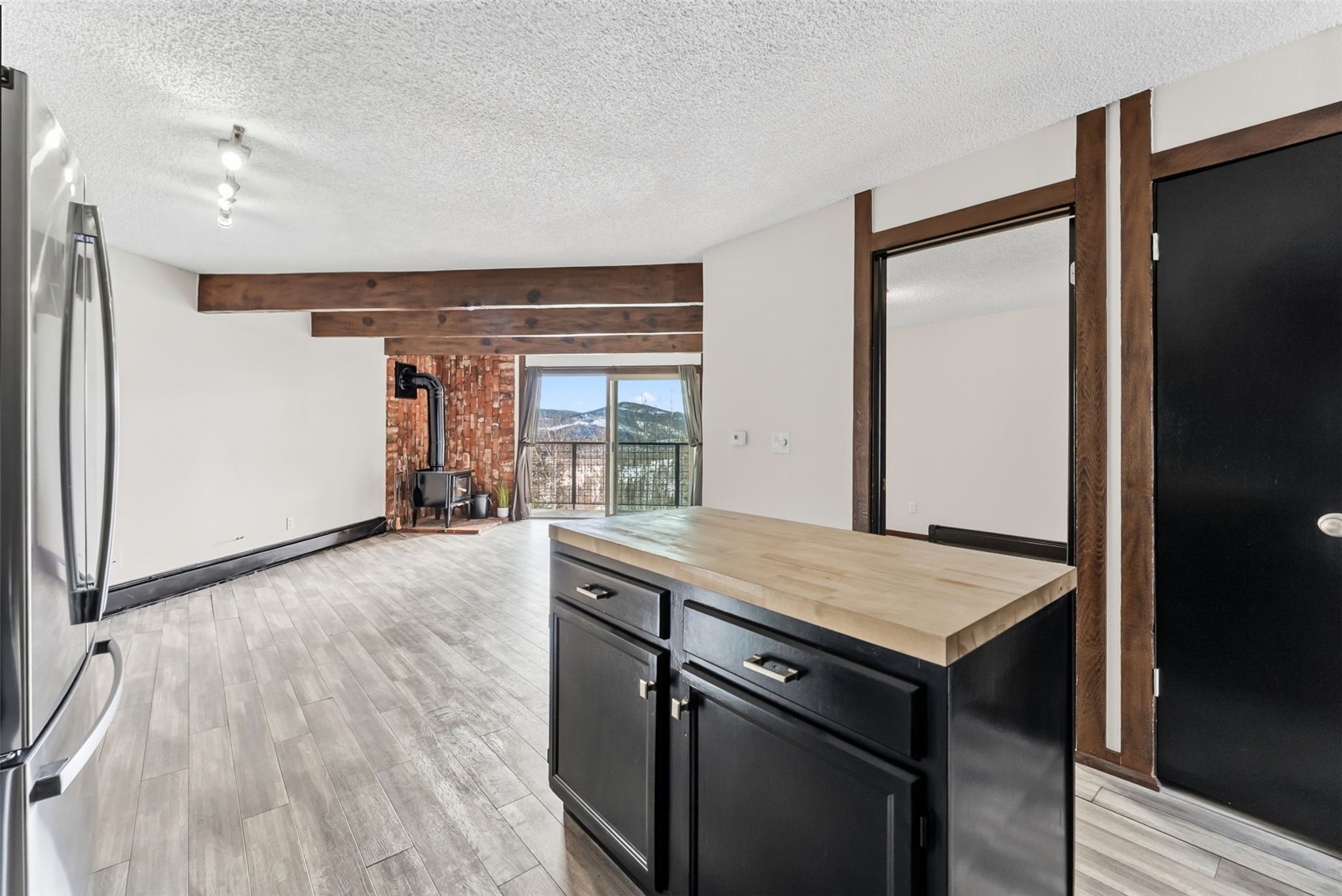 7124 Ryan Gulch Road, Unit 204 Wildernest, CO 80498 - Photo 24 of 36 Kitchen featuring dark cabinetry, butcher block countertops, freestanding refrigerator, light wood-style flooring, and a wood stove