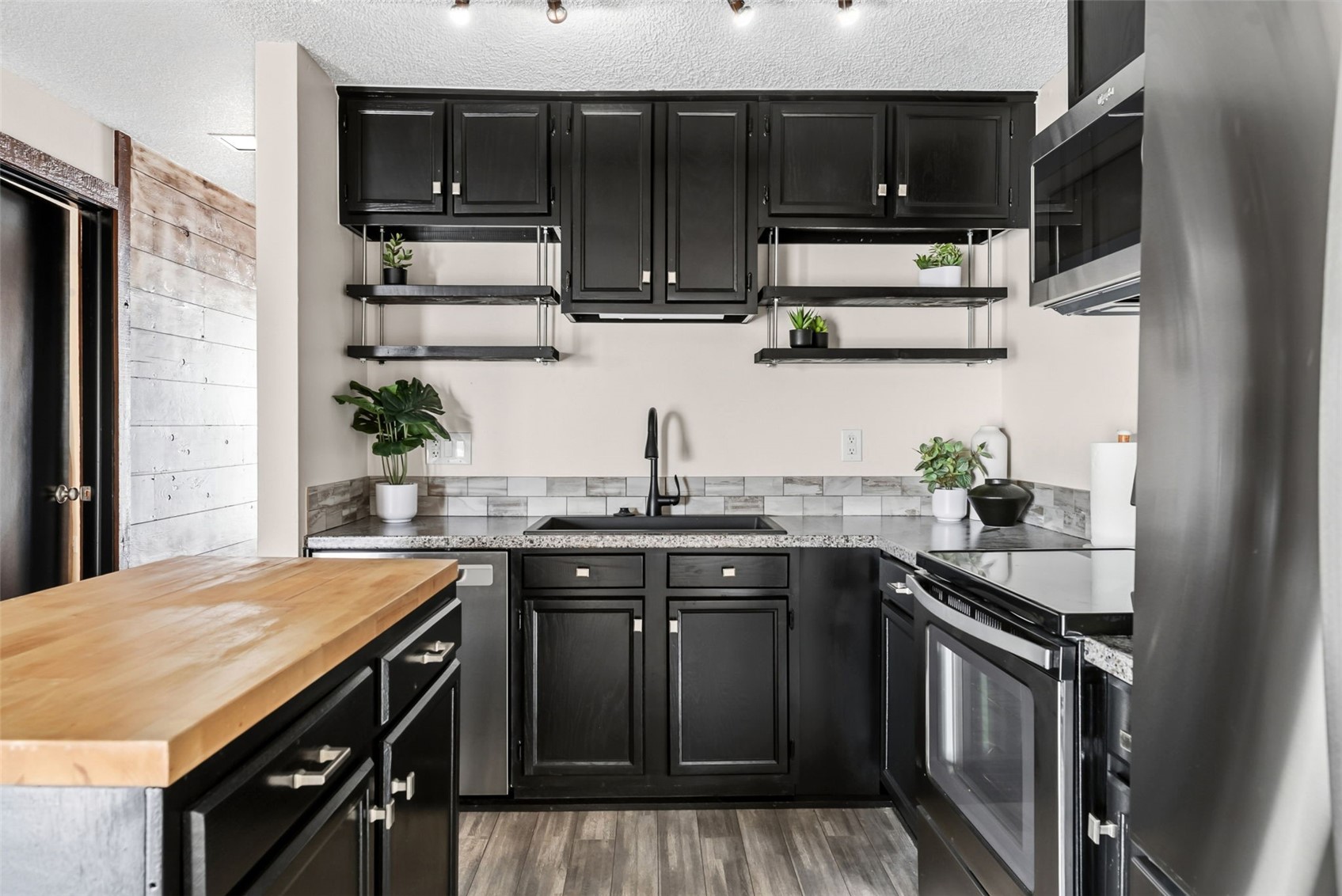 7124 Ryan Gulch Road, Unit 204 Wildernest, CO 80498 - Photo 3 of 36 Kitchen with dark cabinetry, wood counters, stainless steel appliances, open shelves, and a textured ceiling