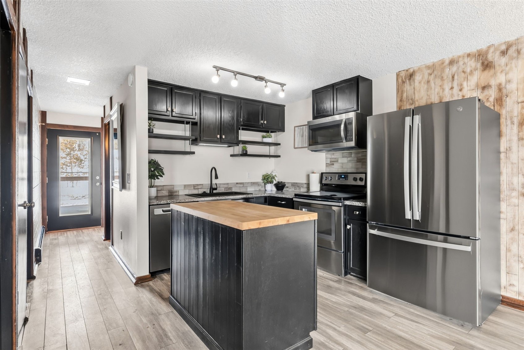7124 Ryan Gulch Road, Unit 204 Wildernest, CO 80498 - Photo 4 of 36 Kitchen with dark cabinets, wood counters, stainless steel appliances, a kitchen island, and a textured ceiling